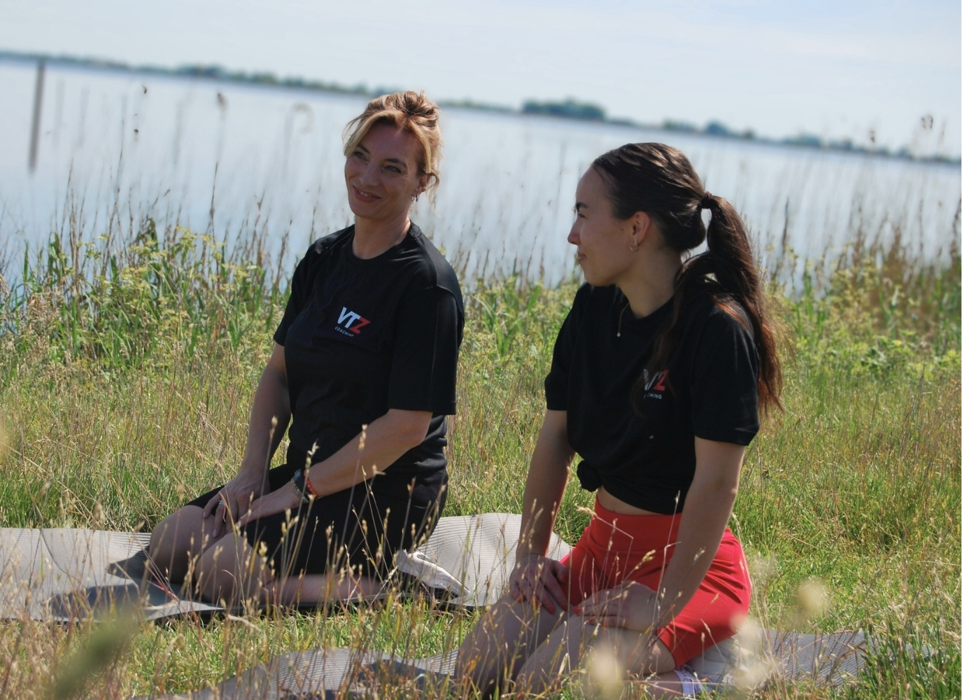 Twee vrouwen tijdens een duo yogales aan het water